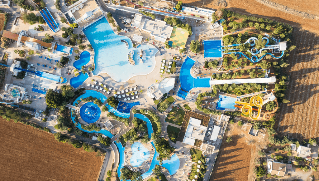 An aerial view of an all-inclusive family resort featuring a vibrant water park with pools, slides, and lazy rivers, designed for fun-filled family vacations.