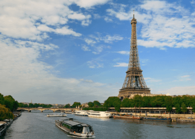 A leisurely river cruise on the Seine with the iconic Eiffel Tower towering in the background under a blue sky.