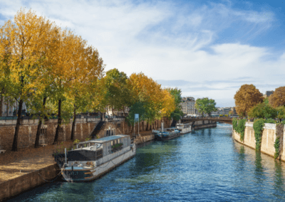 A scenic river cruise in Paris during autumn, with colorful trees lining the Seine River and charming architecture in the background.