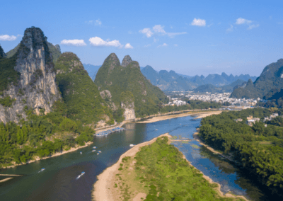 A serene river cruise in China, featuring dramatic limestone karsts and lush greenery along the Li River.