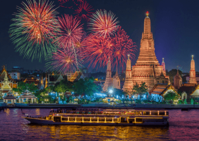 A vibrant evening river cruise in Bangkok, Thailand, with stunning fireworks over the Wat Arun temple.
