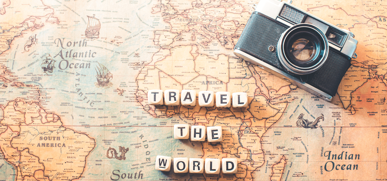Vintage map of the world with a classic camera and letter tiles spelling 'TRAVEL THE WORLD,' symbolizing global exploration and adventure photography.