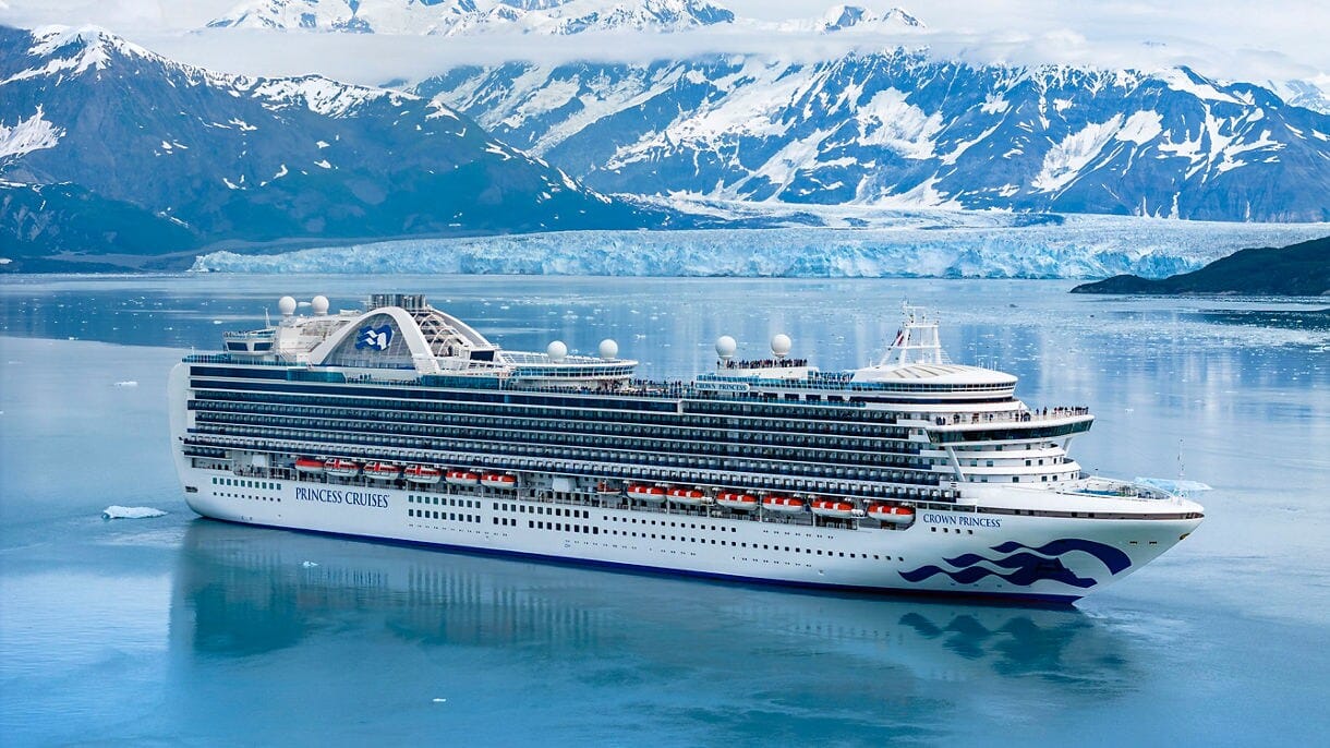 View of a Princess cruise ship sailing through Alaska's icy waters with towering glaciers and rugged mountains in the background