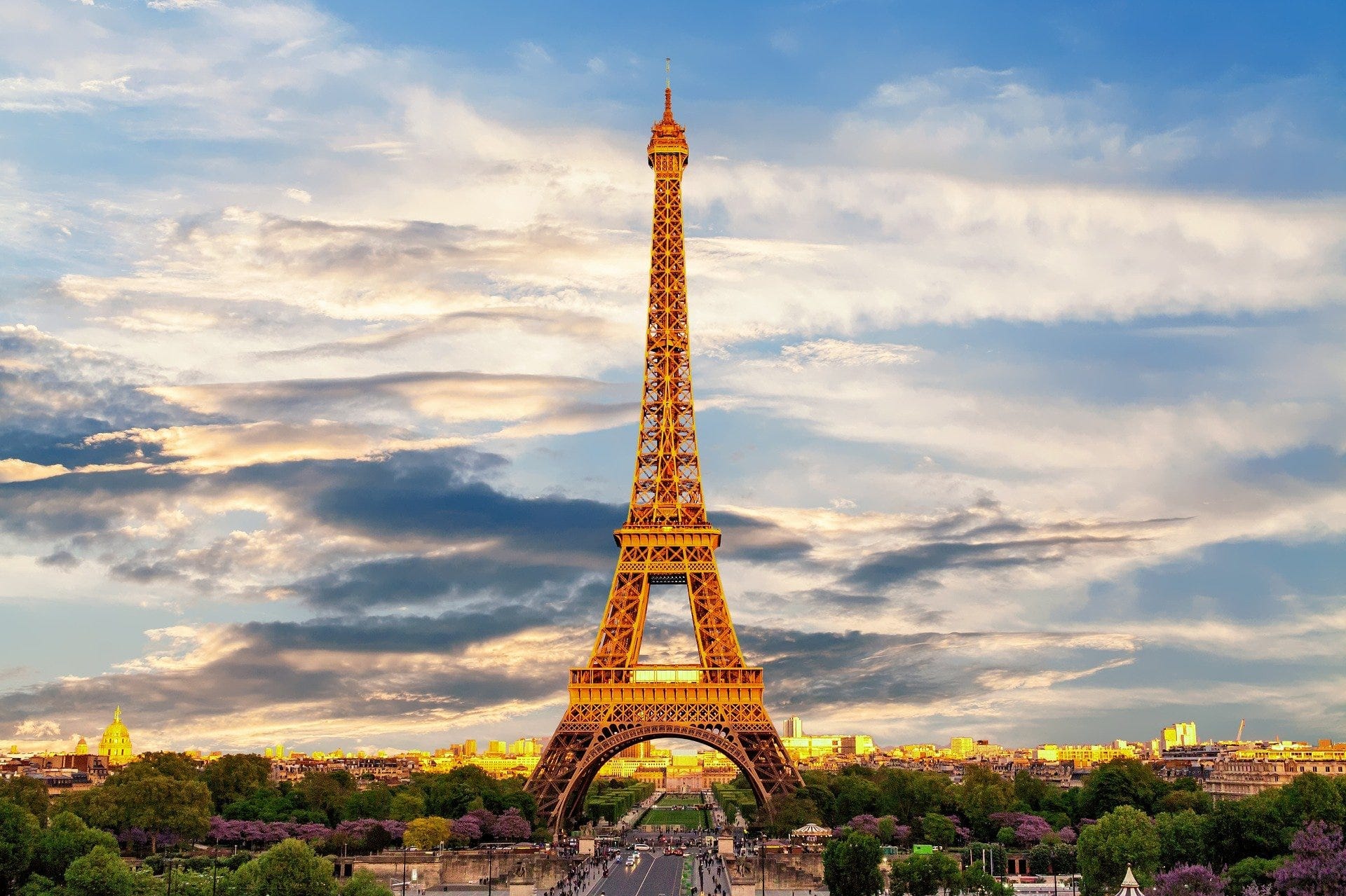 The Eiffel Tower illuminated at sunset with vibrant cityscape of Paris in the background, ideal for romantic getaways and cultural tours.